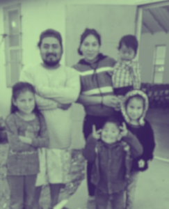A blurred image of a family in Mexico, with two adults and four children posing together, displaying a sense of warmth and togetherness