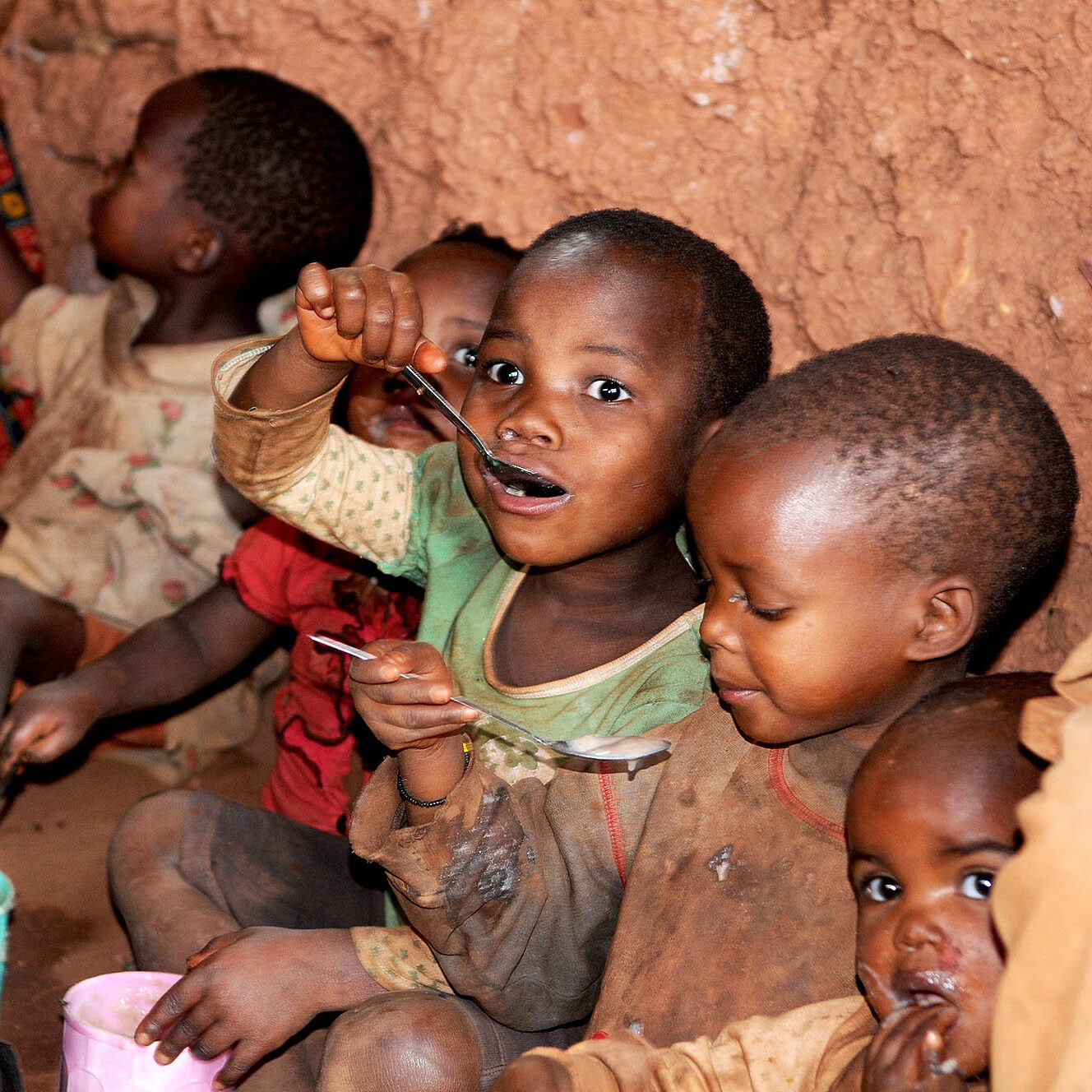 Children in Burundi eating with bright expressions of enjoyment