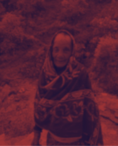 An elder woman smiling in traditional attire with a red overlay