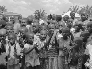 Black and white photograph of a group of joyful children in Burundi clapping and smiling.